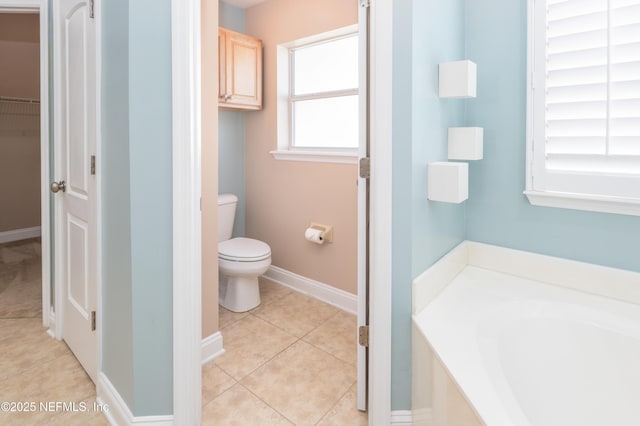 bathroom with a tub to relax in, toilet, and tile patterned flooring