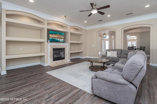 living room featuring ornamental molding, dark wood-type flooring, a fireplace, and built in features