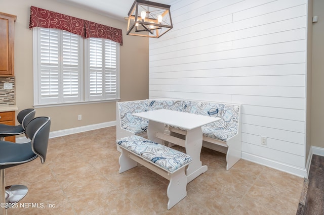 dining space with breakfast area, wooden walls, and a chandelier