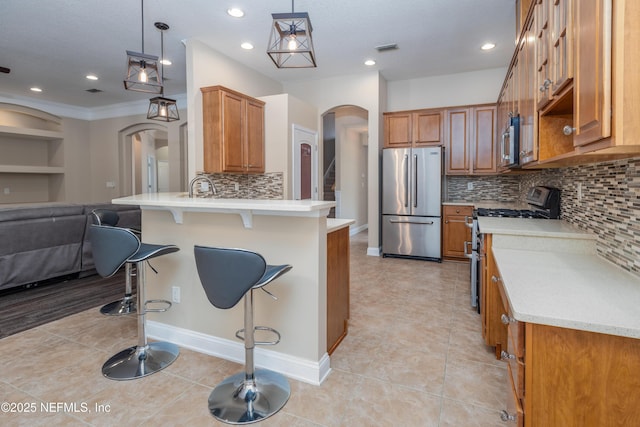 kitchen with hanging light fixtures, light tile patterned floors, appliances with stainless steel finishes, a kitchen breakfast bar, and kitchen peninsula