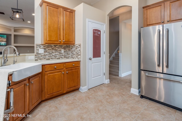 kitchen with sink, light tile patterned floors, high end fridge, tasteful backsplash, and decorative light fixtures