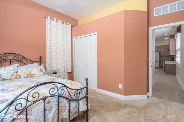 carpeted bedroom featuring refrigerator and a closet