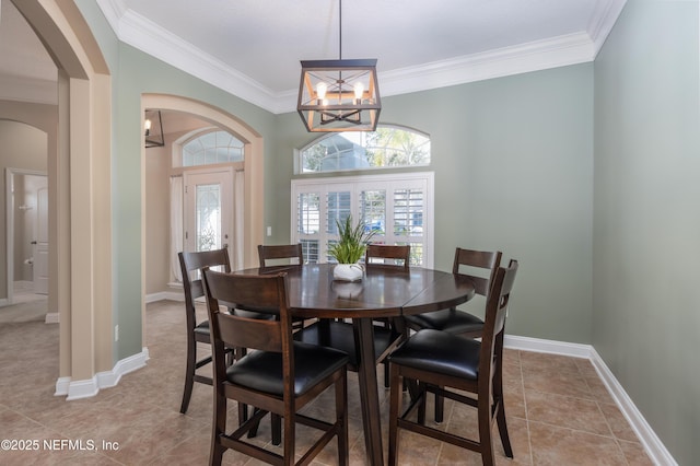 tiled dining room featuring crown molding and a chandelier