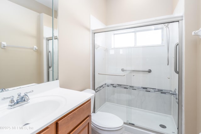 bathroom featuring vanity, toilet, and a shower with shower door