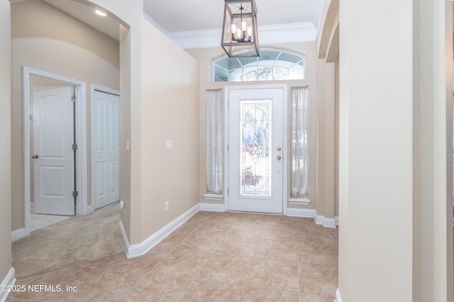 tiled entryway featuring a notable chandelier and crown molding