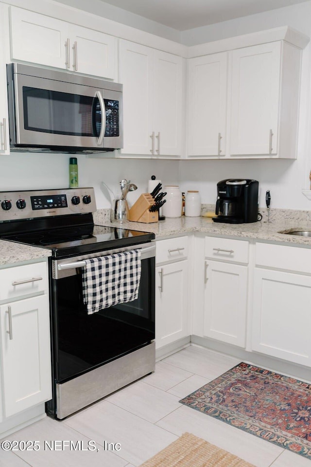 kitchen featuring light stone countertops, appliances with stainless steel finishes, and white cabinets