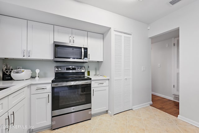 kitchen with white cabinetry, stainless steel appliances, and light tile patterned floors