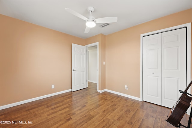 unfurnished bedroom featuring ceiling fan, wood-type flooring, and a closet