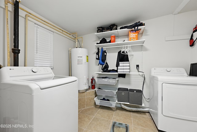 laundry area featuring washing machine and clothes dryer, electric water heater, and light tile patterned floors