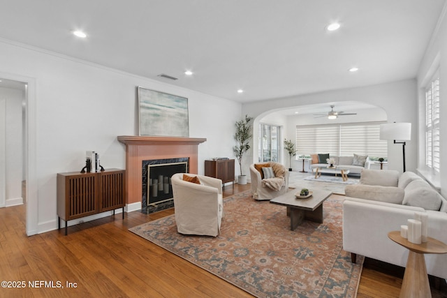 living room featuring wood-type flooring, a premium fireplace, and ceiling fan