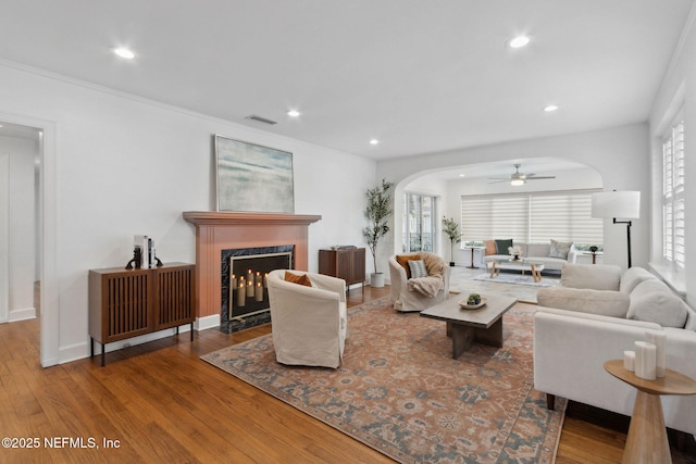 living room featuring hardwood / wood-style flooring, a premium fireplace, and ceiling fan