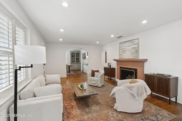 living room featuring crown molding, wood-type flooring, and a high end fireplace