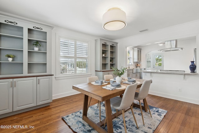 dining area with ornamental molding and dark hardwood / wood-style flooring