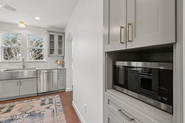 kitchen featuring tasteful backsplash, sink, gray cabinets, and appliances with stainless steel finishes