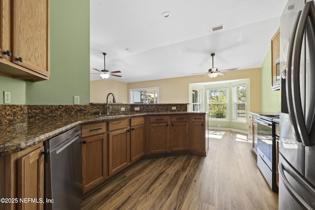 kitchen featuring vaulted ceiling, sink, dark stone countertops, stainless steel appliances, and dark wood-type flooring