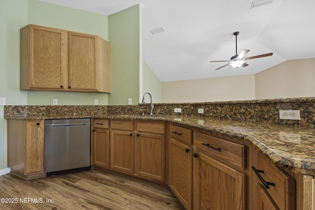 kitchen featuring lofted ceiling, sink, dark stone countertops, wood-type flooring, and stainless steel dishwasher