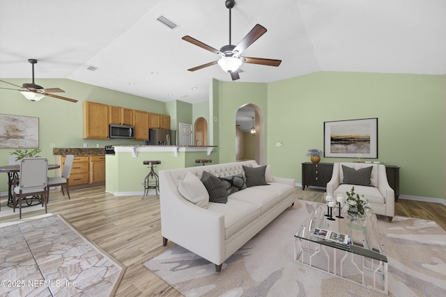 living room featuring lofted ceiling, ceiling fan, and light wood-type flooring