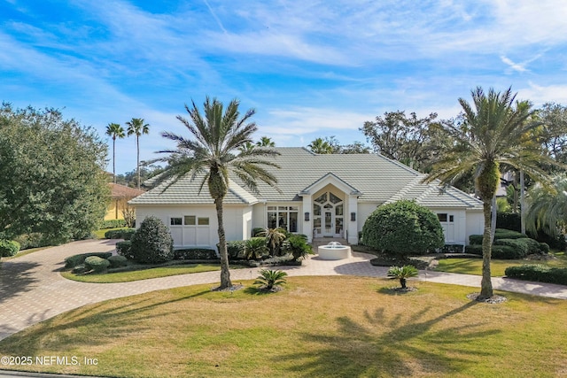 view of front facade with driveway, a front yard, a tile roof, and stucco siding