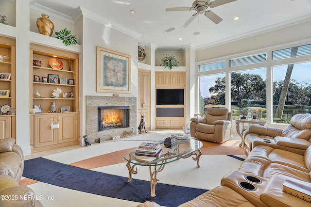 living room with built in features, ceiling fan, a high ceiling, a high end fireplace, and ornamental molding