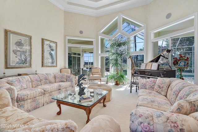 carpeted living room with plenty of natural light, ornamental molding, and a high ceiling