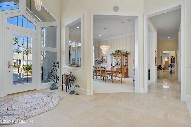 entryway with ornamental molding, a towering ceiling, and an inviting chandelier