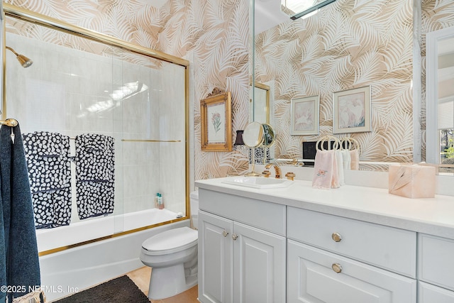 full bathroom featuring vanity, bath / shower combo with glass door, and toilet