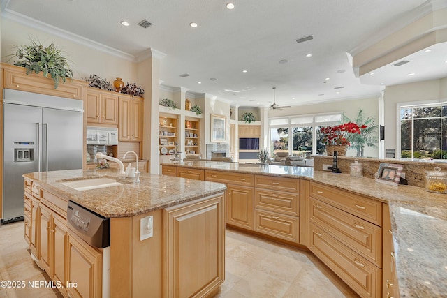 kitchen with light stone countertops, built in refrigerator, an island with sink, and light brown cabinets