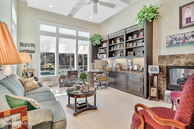 living room with ceiling fan, light colored carpet, a high end fireplace, and built in desk