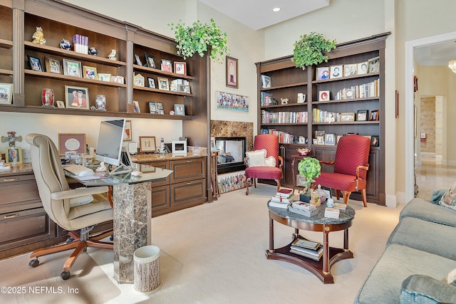 office featuring a tiled fireplace, light colored carpet, and built in desk