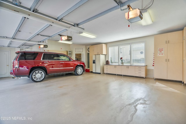 garage featuring a garage door opener and white refrigerator with ice dispenser