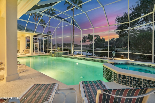 pool at dusk featuring an in ground hot tub, a patio, and glass enclosure