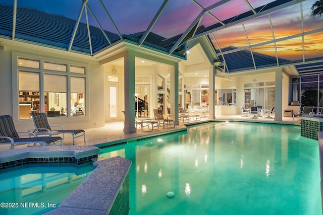 pool at dusk featuring a patio area and glass enclosure