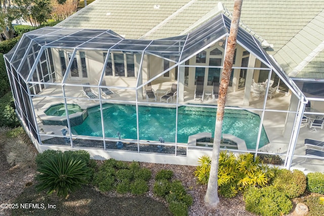 view of pool featuring an in ground hot tub, glass enclosure, and a patio area