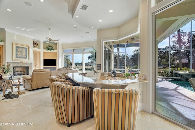 living room with ceiling fan, ornamental molding, and a high end fireplace