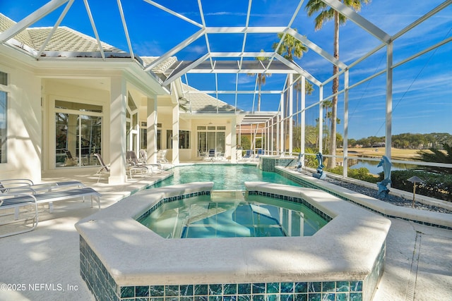 view of pool featuring an in ground hot tub, a water view, glass enclosure, and a patio area