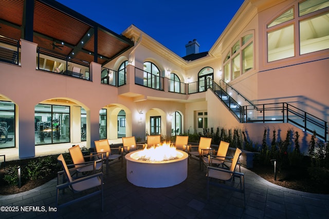 patio at night featuring an outdoor fire pit and stairs
