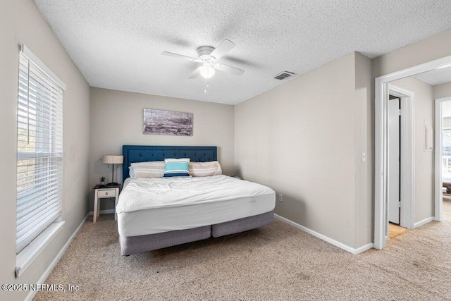 bedroom featuring ceiling fan, light colored carpet, and a textured ceiling