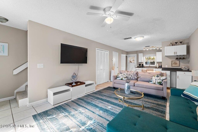 living room featuring light tile patterned flooring, ceiling fan, and a textured ceiling