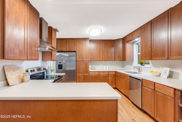 kitchen with appliances with stainless steel finishes, sink, wall chimney range hood, and light hardwood / wood-style flooring