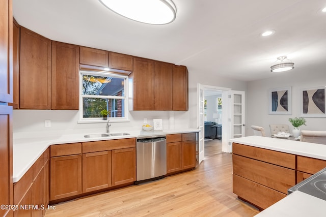 kitchen with sink, stainless steel dishwasher, and light hardwood / wood-style flooring