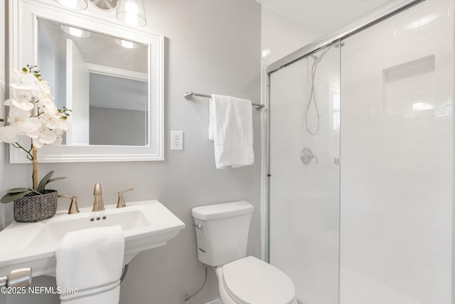 bathroom with toilet, a shower with shower door, and sink