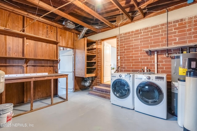 washroom featuring independent washer and dryer, brick wall, and water heater