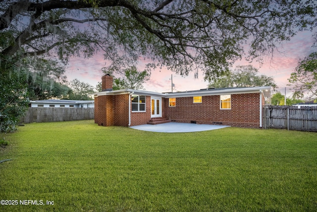 back house at dusk with a yard and a patio area