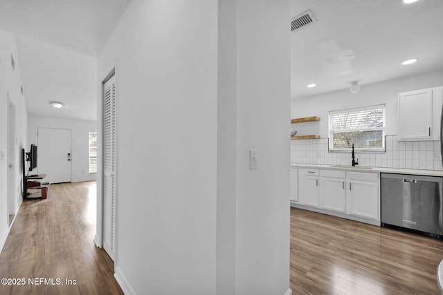 corridor with light hardwood / wood-style floors, sink, and a textured ceiling