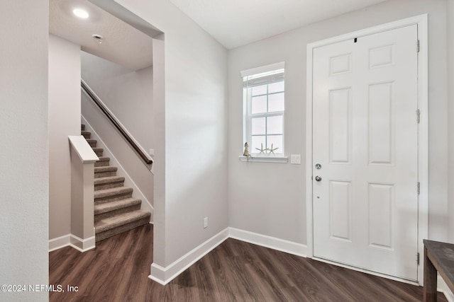 foyer featuring dark wood-type flooring, stairway, and baseboards