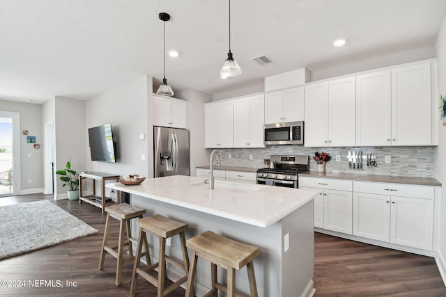 kitchen with dark wood-style floors, stainless steel appliances, tasteful backsplash, visible vents, and a sink