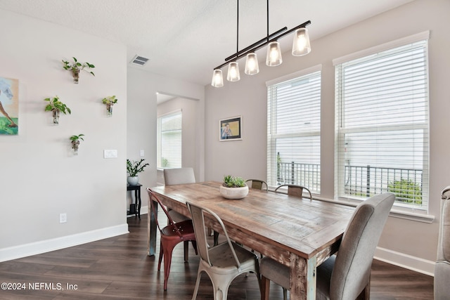 dining area with dark wood-style floors, baseboards, visible vents, and a textured ceiling