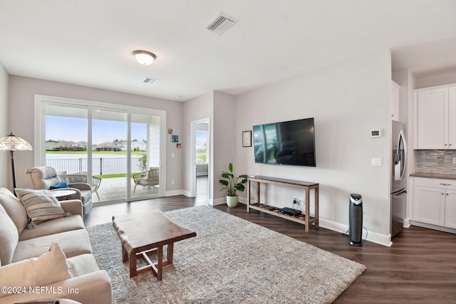 living area featuring a textured ceiling, dark wood-type flooring, visible vents, and baseboards