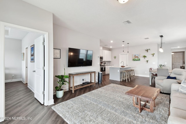 living area featuring visible vents, baseboards, dark wood finished floors, and recessed lighting