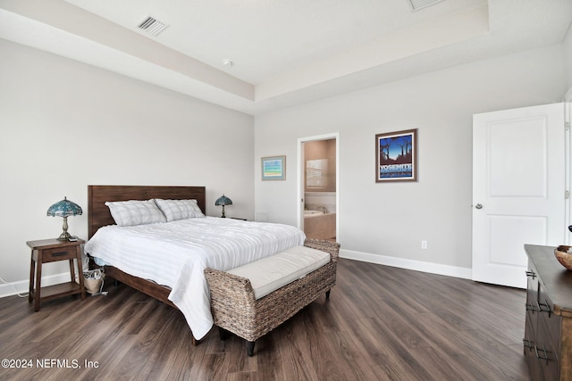 bedroom with a tray ceiling, dark wood-type flooring, visible vents, and baseboards